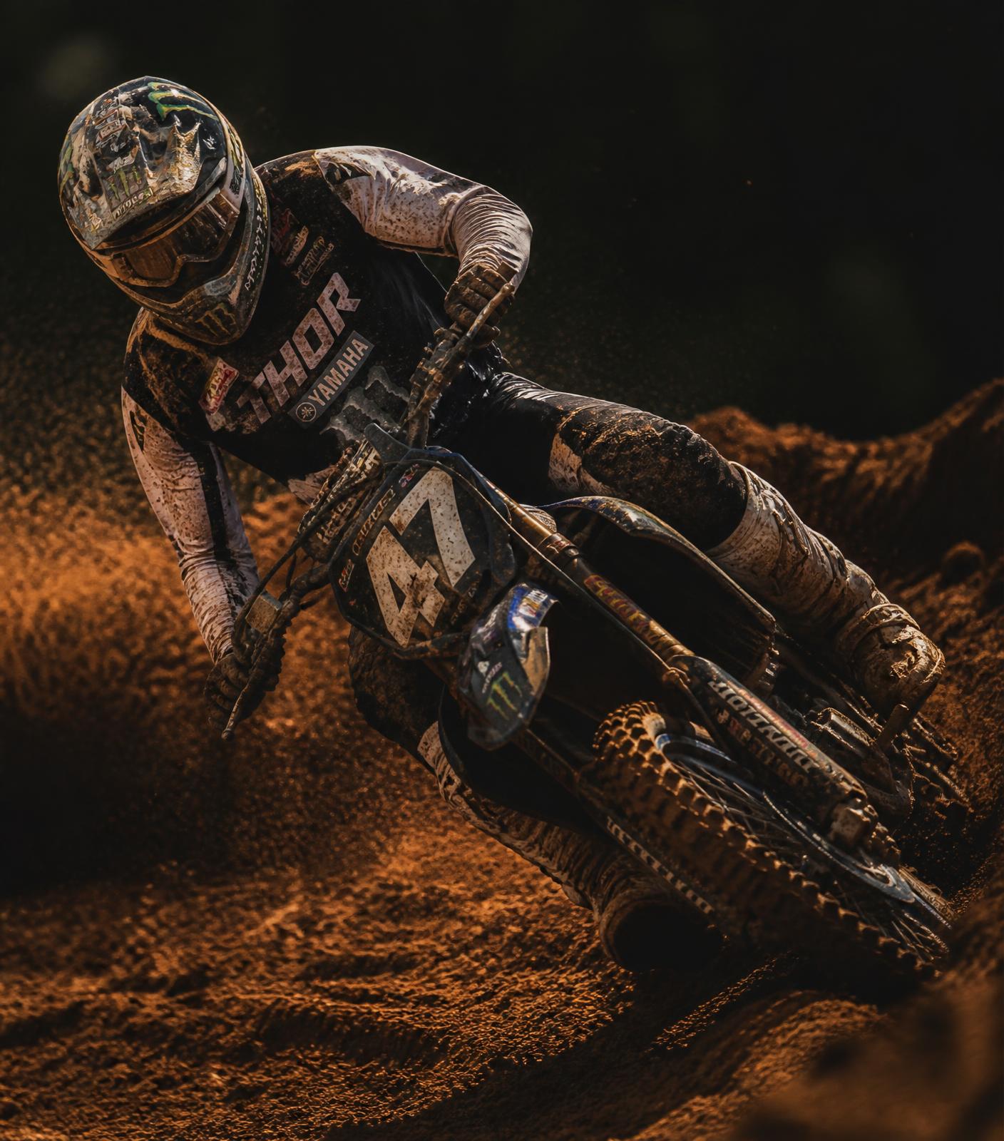 Piloto de motocross inclinado em uma curva levantando terra